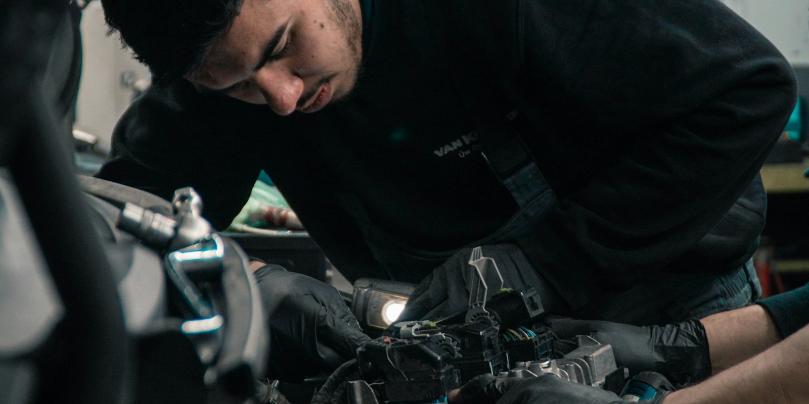 Technician working under the hood of a vehicle in the workshop